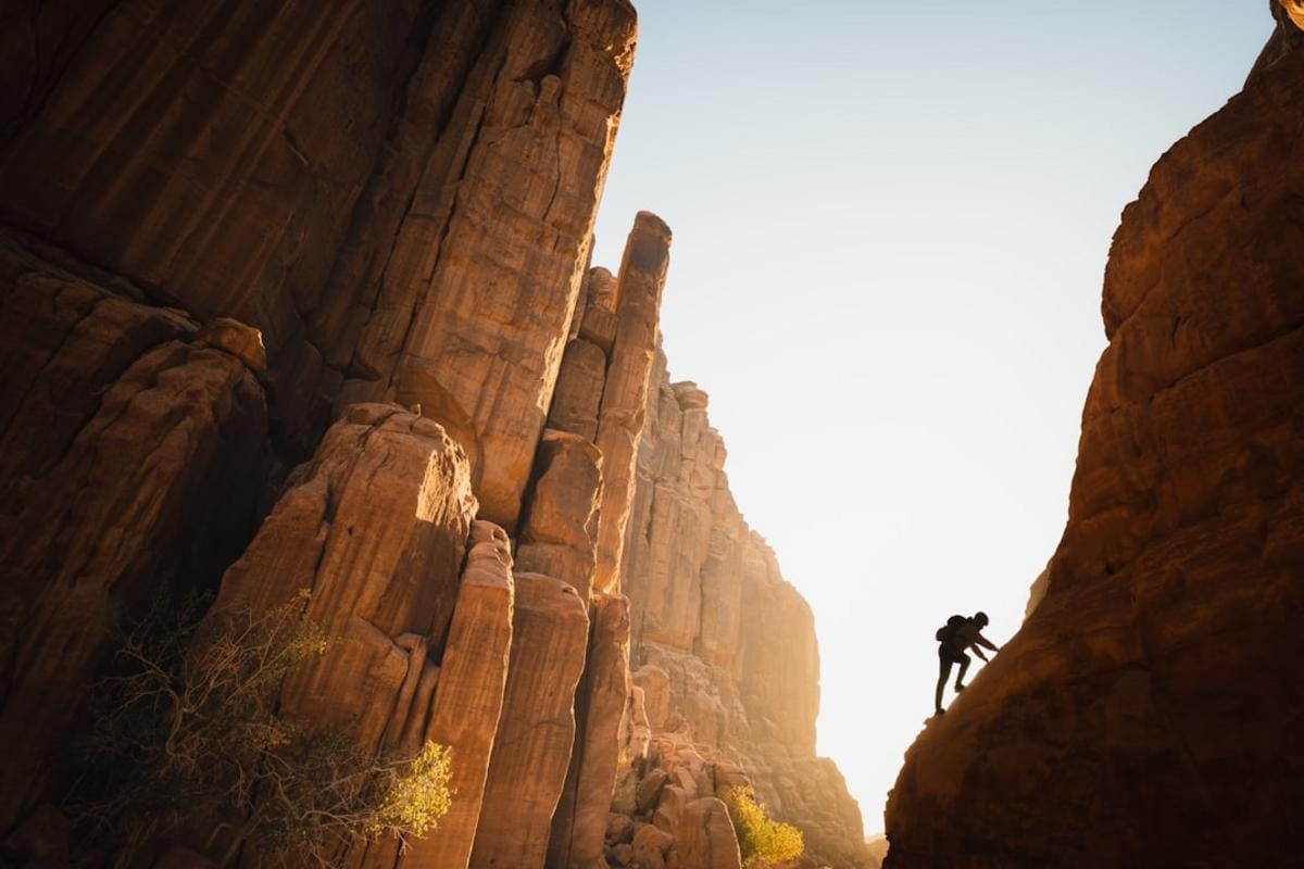 motivasyon teknikleri A person standing atop a mountain at sunrise, symbolizing empowerment, motivation, and inner strength, with vibrant natural scenery.
